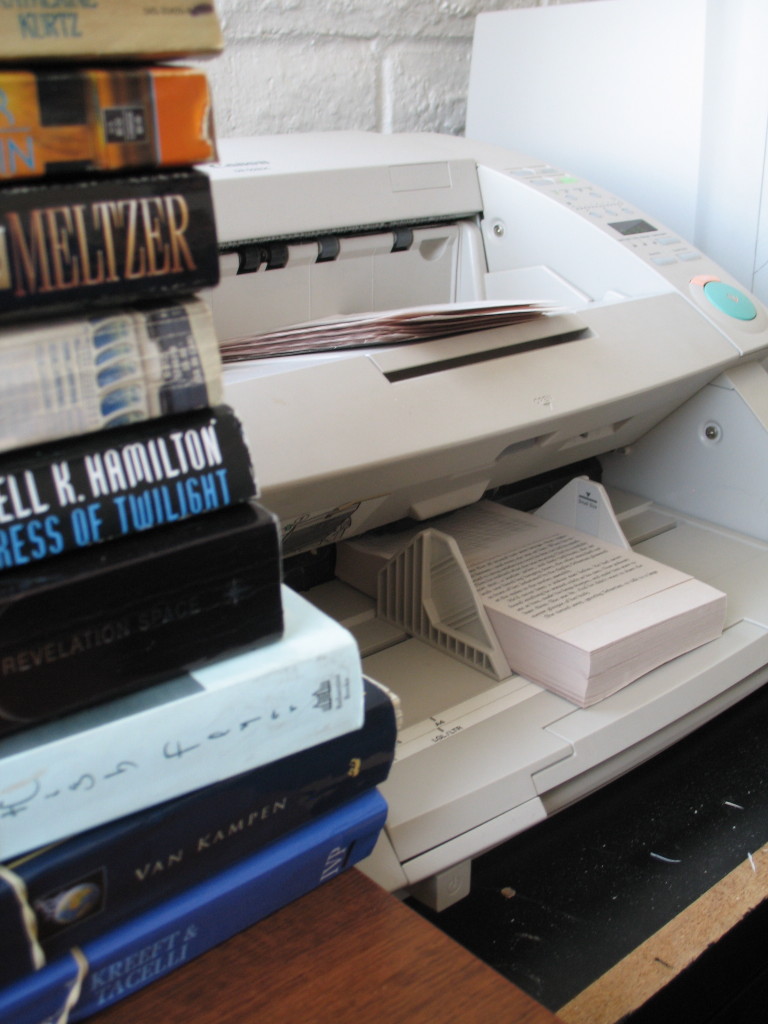 Image of Bookshare  scanner with printed books piled on the side.