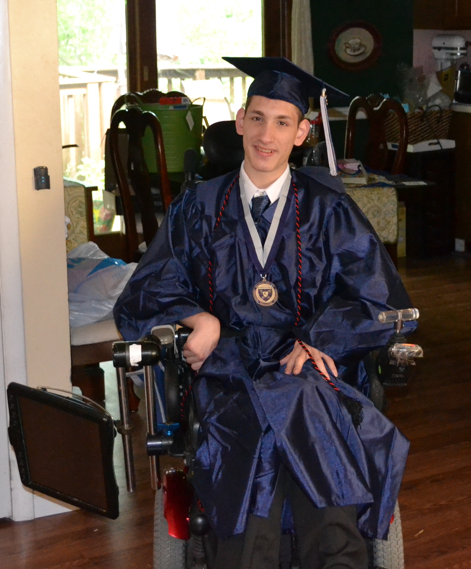Student in wheel chair wearing a graduation cap and gown.