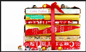 colorful books stacked high with a red ribbon tied in a bow. 
