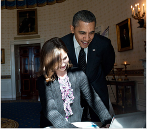 President Obama looking over the shoulder of a young female student using a computer for learning.