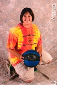 Kelly Schneider kneeling with a basketball.