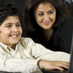 Parent working with son to read accessible books on a computer.