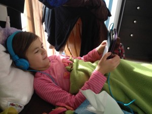 Lilly reading iPad in bed with headphones