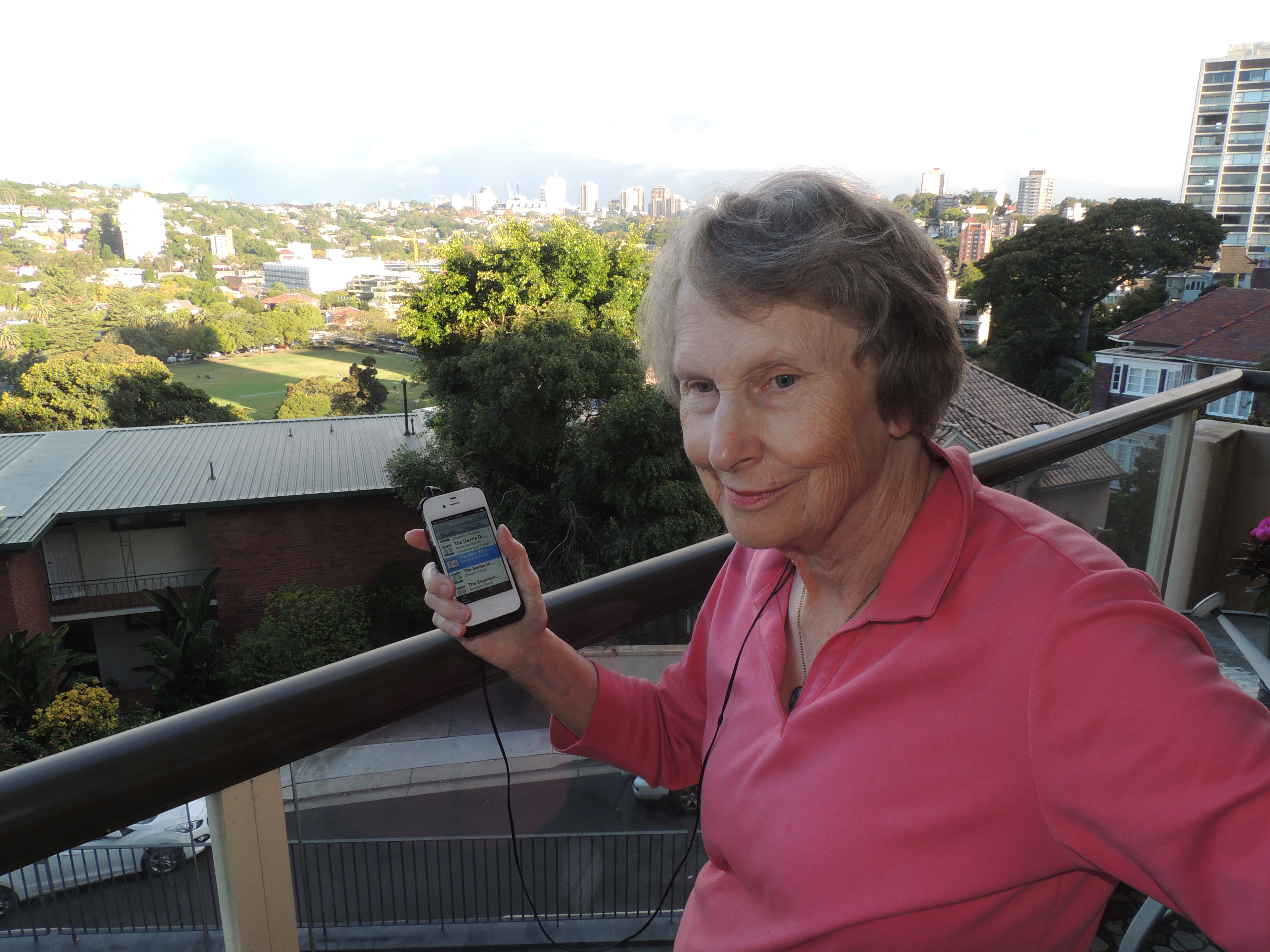 Fran, a Canadian with a visual impairment, listens to a NY Times bestseller on her smartphone, for her book club.