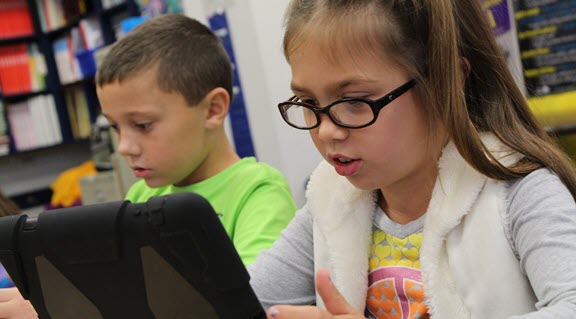 a young girl wearing glasses is using an iPad