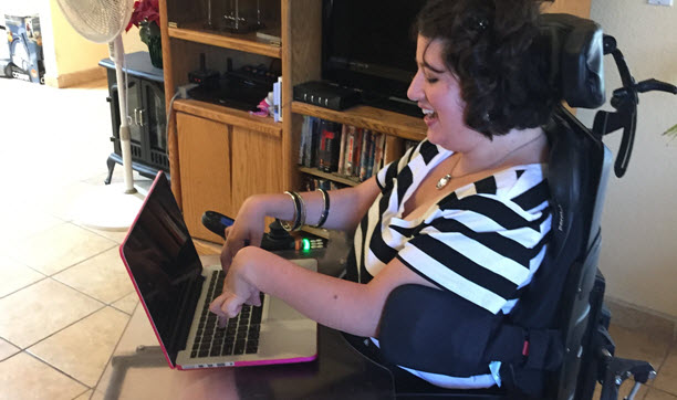 Jessica Pinto is sitting in a wheelchair and using a Macbook