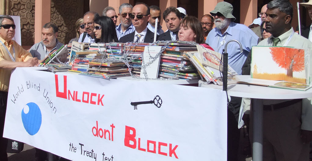 Members of the World Blind Union stand behind a table containing books in chains
