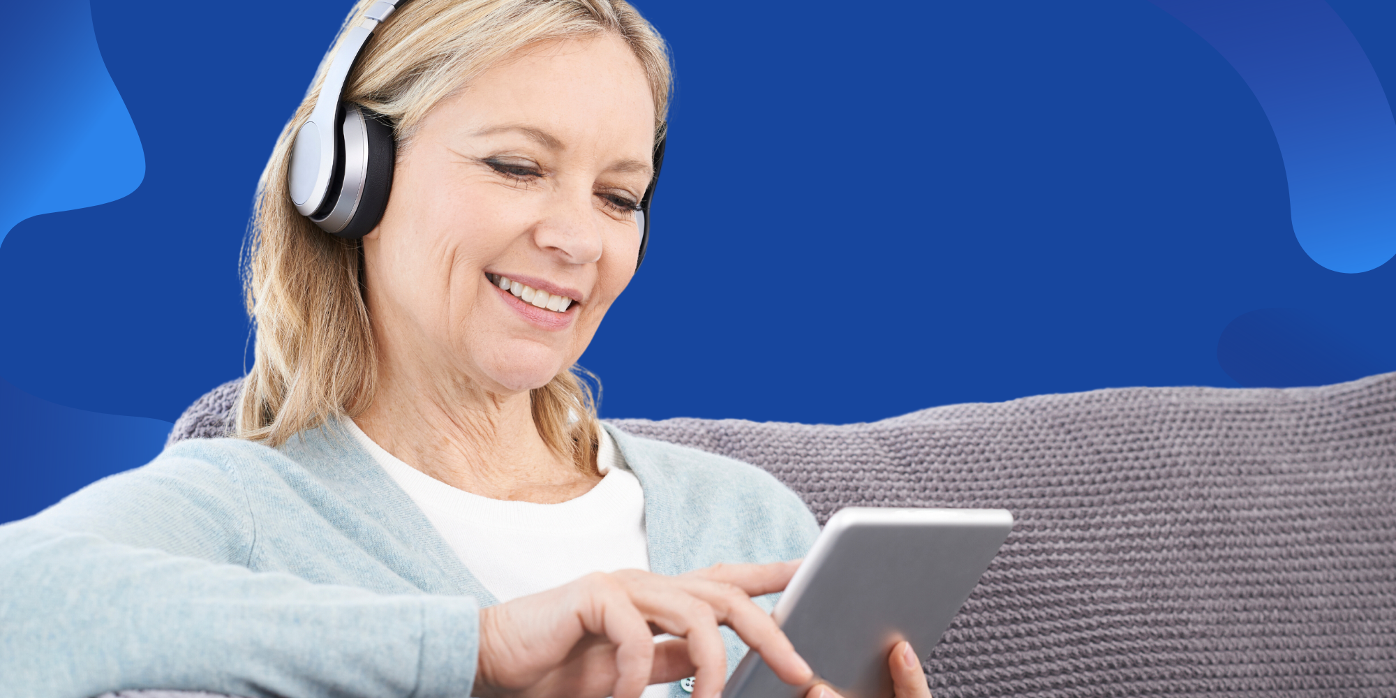 Middle aged woman reading on tablet with headphones.